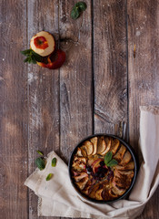 apple pie on wooden background with copy space. Fresh apples with tasty homemade pie on wooden table.