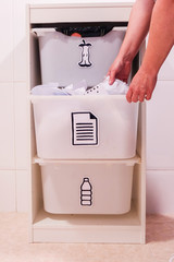 Woman putting papers in recycling bin in the kitchen