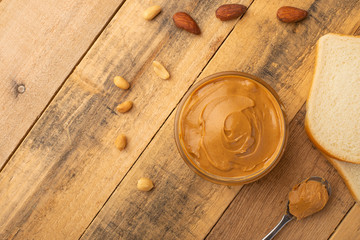 peanut butter, toast and nuts on a wooden texture, top view