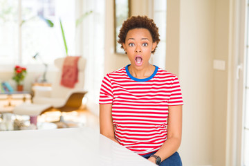 Young beautiful african american woman at home afraid and shocked with surprise expression, fear...