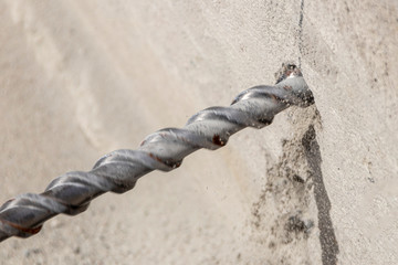 People are using electric drill,He drilled concrete to put steel anchor.