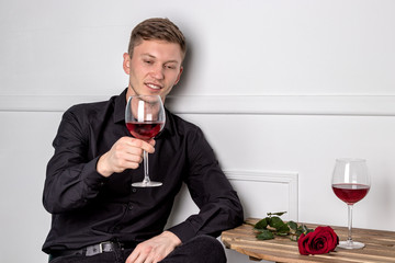 Young handsome man sitting by table in cafe while waiting for his girlfriend