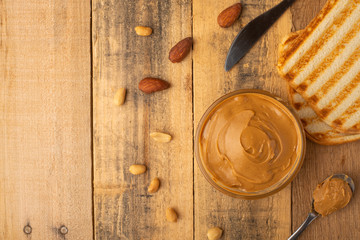 peanut butter, toast and nuts on a wooden texture, top view