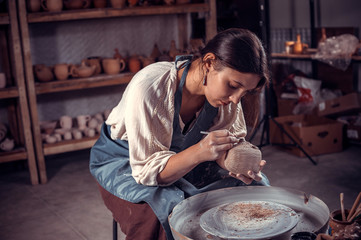 Stylish pottery woman sculptor works with clay on a Potter's wheel and at the table with the tools. Inspiration and creativity.