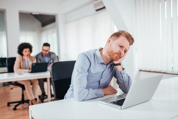 Fototapeta premium A young desperate businessman in his office looking at laptop.