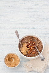 Delicious oatmeal in a white bowl, dates fruits, cocoa and vegan milk. healthy breakfast on light blue background. top view. free space