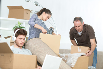 family preparing cardboard boxes idle boy on laptop