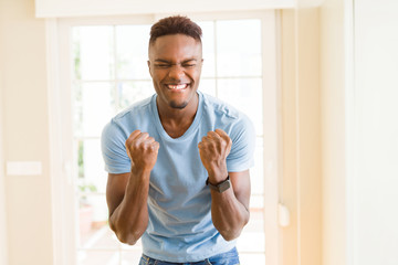 African American man screaming very excited and celebrating success and victory, smiling happpy and...