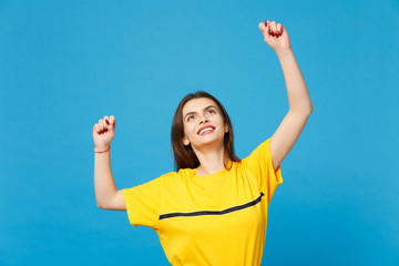 Portrait of smiling happy young woman in vivid casual clothes looking up, clenching fists like...