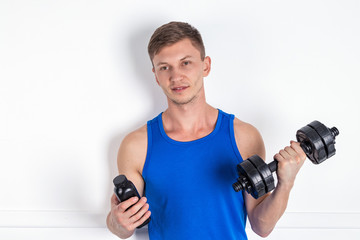 Fototapeta na wymiar Handsome young man in blue shirt lifting dumbbell. White background