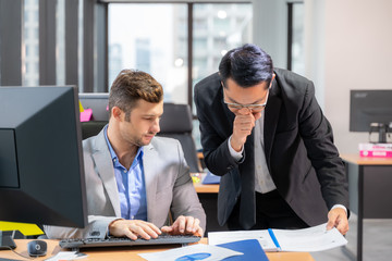 Group of young business people working and communicating while sitting at the office desk together.