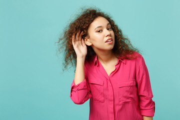Portrait of curious african girl in casual clothes eavesdrop with hearing gesture isolated on blue...