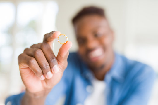 Close up of african man hand holding golden alliance as romatic marriage symbol smiling cheerful