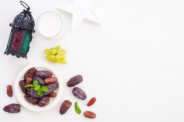 Ramadan food and drinks concept. Ramadan Lantern with Milk, dates fruit, grape and Mint leaves on a white wooden table background. Top view, Flat lay.