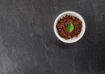 Bowl of powder cocoa. Top view, gray stone background.