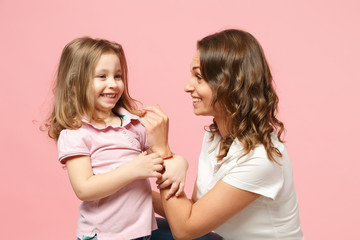 Woman in light clothes have fun with cute child baby girl. Mother, little kid daughter isolated on pastel pink wall background, studio portrait. Mother's Day, love family, parenthood childhood concept