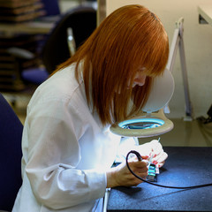Woman Soldering a circuit board in her tech office.Close up of female engineer Middle-aged quality...