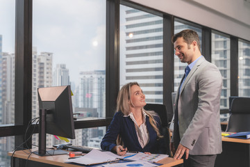 Group of young business people working and communicating while sitting at the office desk together.