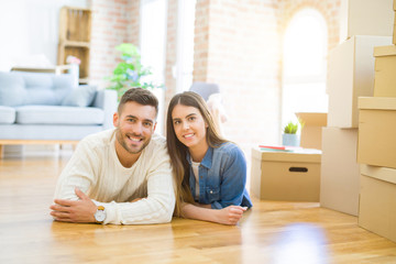 Young beautiful couple lying on the floor of new house, smiling in love very happy for moving to new apartment