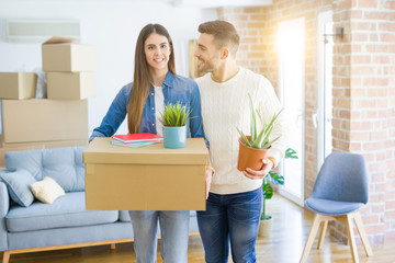 Beautiful young couple moving to a new house, smiling happy holding cardboard boxes at new apartment