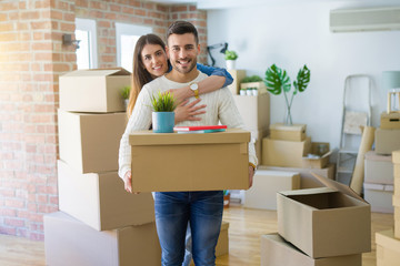 Fototapeta na wymiar Beautiful young couple moving to a new house, smiling happy holding cardboard boxes at new apartment
