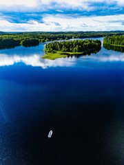 Aerial view of fishing boat in blue lake landscape with green forests on a sunny summer day in...