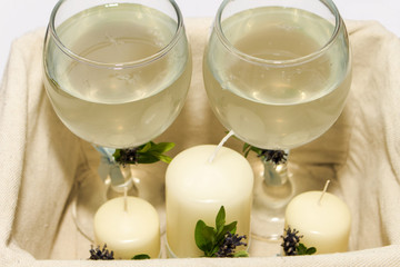 Transparent wine glasses for the bride and groom, decorated with a flower and white candles