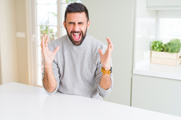 Handsome hispanic man wearing casual sweater at home celebrating mad and crazy for success with...