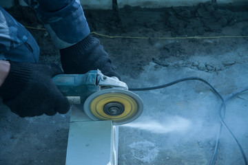 Repair and construction of buildings. The disk of the circular grinding machine rotates cuts white brick. Hands of a worker working in black protective gloves
