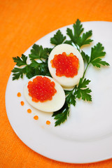 Eggs stuffed with smoked salmon and parsley decor on a plate, orange background