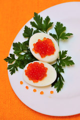 Eggs stuffed with smoked salmon and parsley decor on a plate, orange background