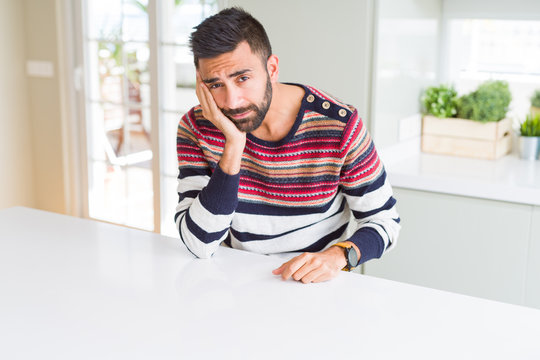 Handsome hispanic man wearing stripes sweater at home thinking looking tired and bored with depression problems with crossed arms.