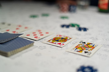 Poker community cards uncovered and chips as bets placed on a table with white tablecloth.