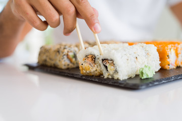 Close up of colorful sushi asian food, man hands holding sushi pieces using chopsticks