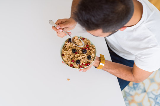 Above angle of handsome man eating healthy cereals for breakfast in the morning
