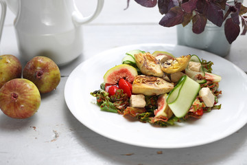 Dietary salad with figs, artichoke, cucumber, cherry tomatoes, feta on rucola leaves poured with raspberry sauce.