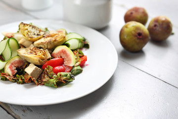 Exquisite salad with figs, artichoke, cucumber, tomatoes, feta on lamb's lettuce leaves topped with raspberry sauce.