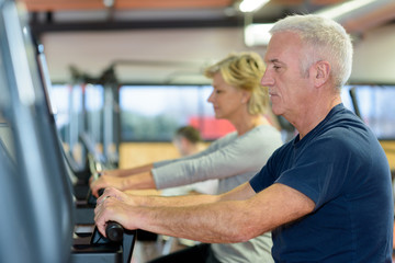 beautiful fit senior couple in gym doing cardio work out