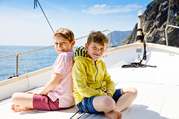 Fototapeta na wymiar Two little kid boys, best friends enjoying sailing boat trip. Family vacations on ocean or sea on sunny day. Children smiling. Brothers, schoolchilden, siblings having fun on yacht.