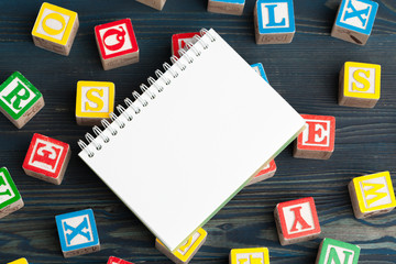 Notepad on wooden table and wood alphabet blocks