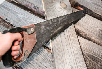 Man holding a saw. Old wooden planks.