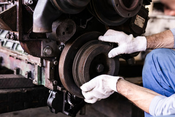 Mechanic repairs old motor of truck in a car repair station. Disassemble engine block vehicle. Motor capital repair. Car service concept