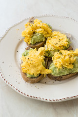 Scrambled Eggs with Avocado on Toast Bread for Breakfast.