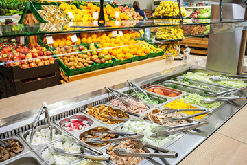 Salad bar on background of shop-windows with vegetables and fruits in supermarket.