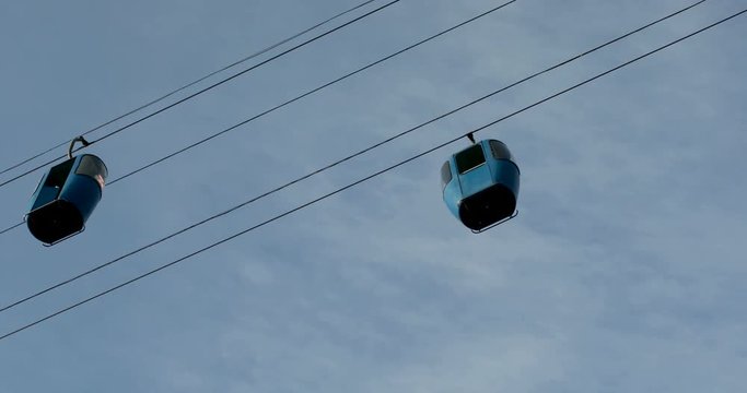 Cableway telpher on a background of blue sky in sunset time different colors diagonal movement