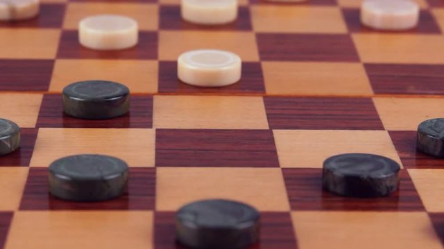 Humans game to the malachite checkers and marble checkers on a wooden checkerboard. Close-up