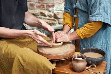 A closeup of a hand of two artisans making a jug