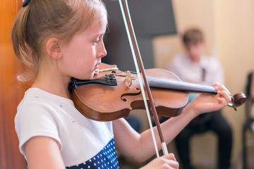 Child, little girl playing violin indoors in music class