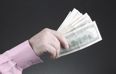 hand of a man in a pink shirt holding dollar bills