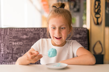 Little girl eating ice cream in a cafe. Adorable little girl eating ice cream at summer. Happy girl eating ice cream in cafe